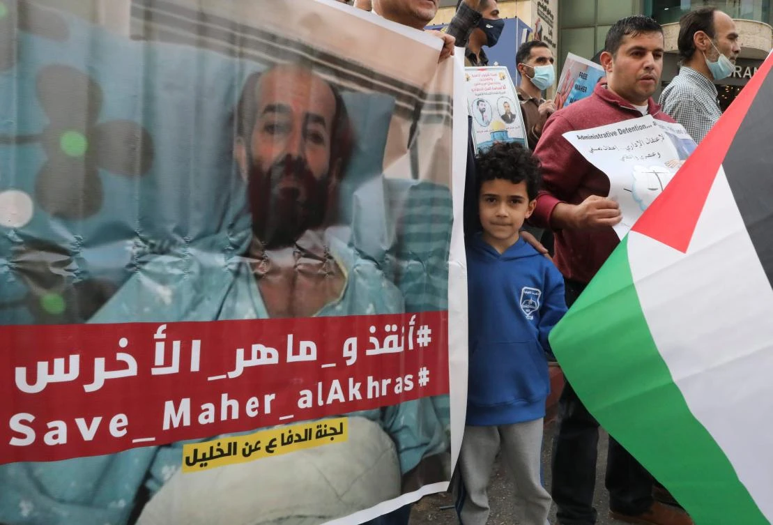 Palestinians carry placards demanding the release of administrative detainee in Israeli custody Maher al-Akhras during a demonstration Hebron on November 3, 2020, after his health has deteriorated while on hunger strike for nearly 100 days. (AFP)