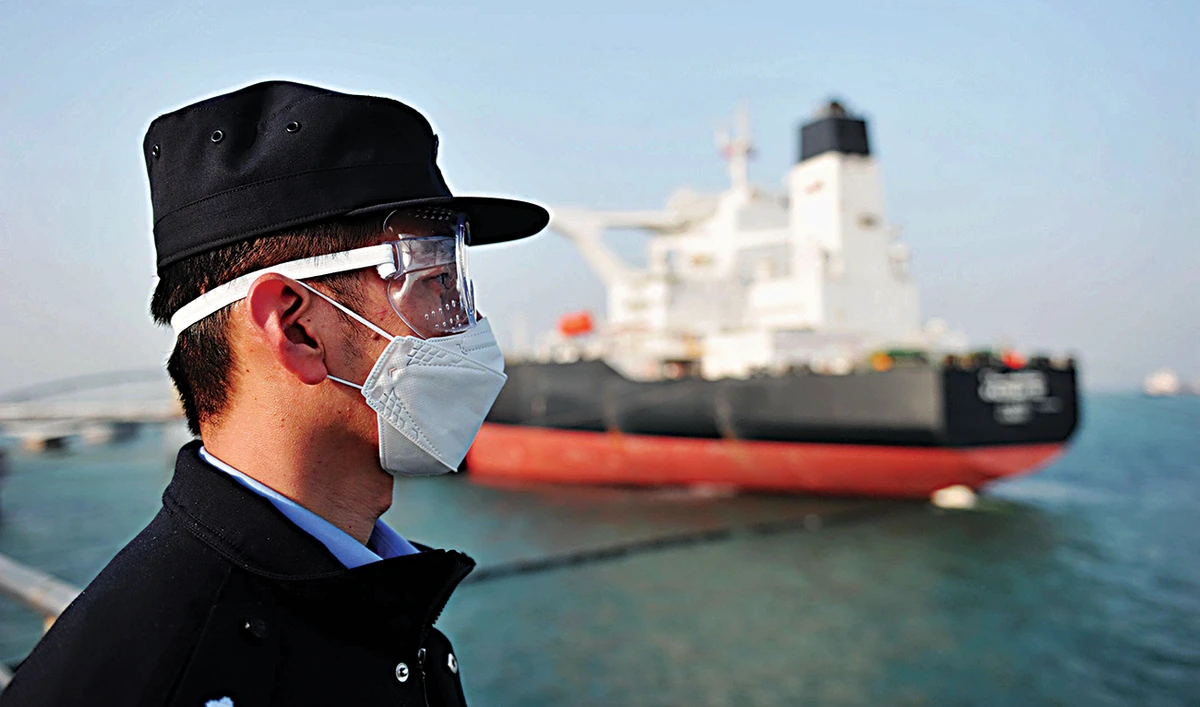 A police officer keeps watch as a Kuwaiti oil tanker unloads its cargo at Qingdao in China’s eastern Shandong province. (AFP)