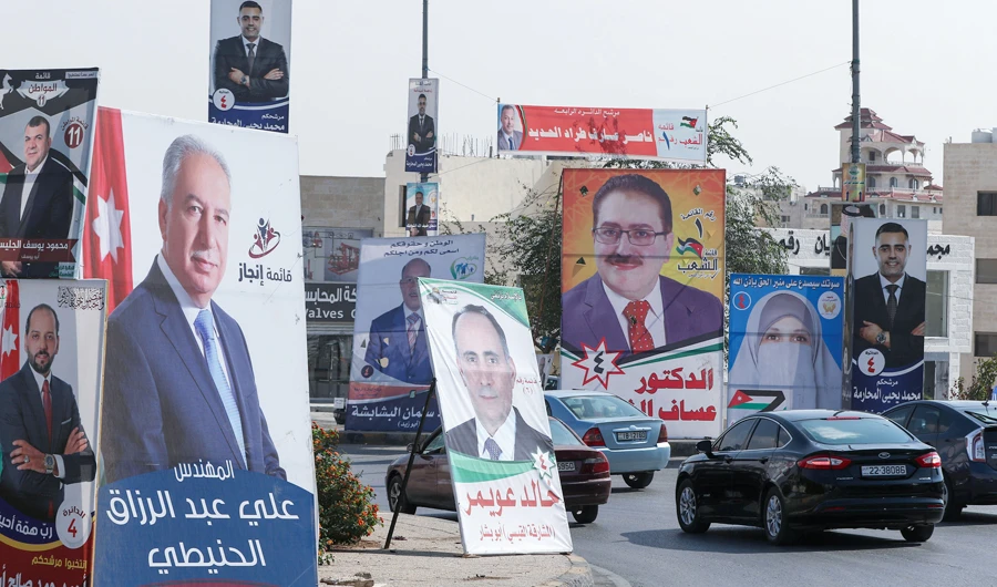 Cars advance on a road lined with campaign banners and slogans of candidates for the upcoming Jordanian parliamentary elections in Amman. (AFP)