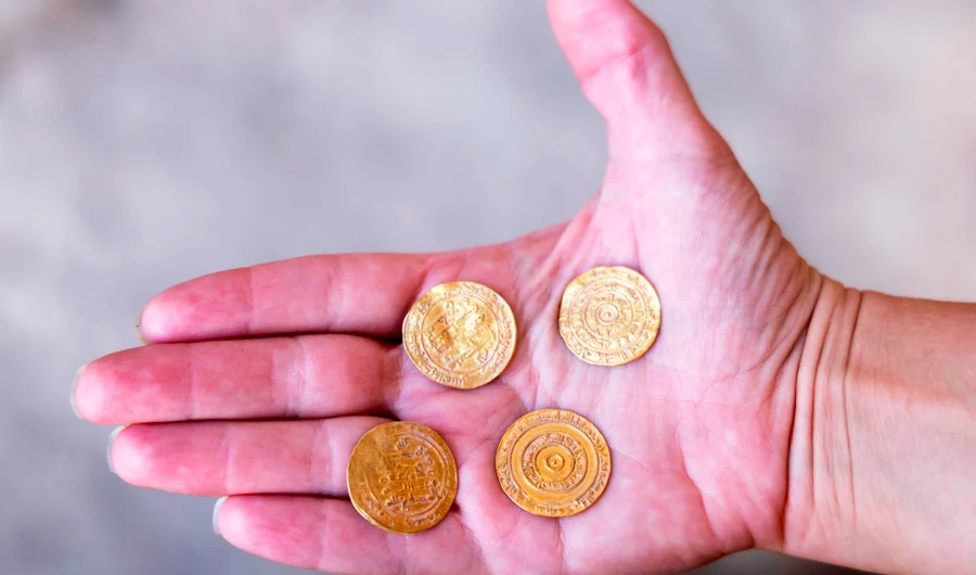 Archaeologist at the Israel Antiquities Authority Evgeniya Rabinovich shows a small pottery jug with four pure gold coins found inside it, at the archaeological rescue excavation site in the Old City of Jerusalem, on November 9, 2020. (AFP)