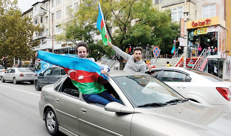 People wave natinonal flags as they celebrate on the streets after Azerbaijan’s President Ilham Aliyev said the country’s forces had taken the city of Shusha in Nagorno-Karabakh, in Baku, on Sunday. (Reuters)