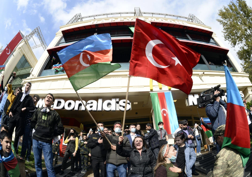 Azerbaijanis celebrate waving national and Turkish flags in Baku, Azerbaijan, Tuesday, Nov. 10, 2020. Armenia and Azerbaijan announced an agreement early Tuesday to halt fighting over the Nagorno-Karabakh region of Azerbaijan under a pact signed with Russia that calls for deployment of nearly 2,000 Russian peacekeepers and territorial concessions. (AP Photo)