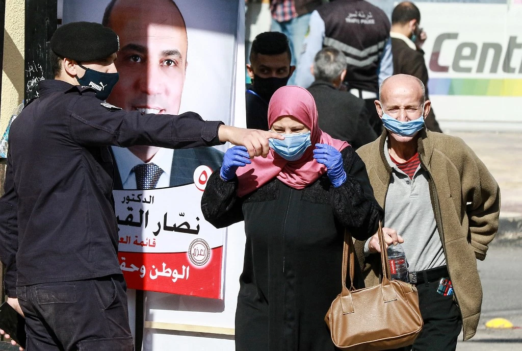 A member of the Jordanian security forces directs voters outside a polling station in Amman on November 10, 2020. (AFP)