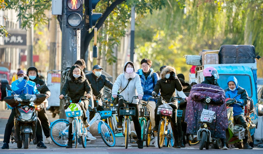 People wearing face masks to protect against the coronavirus wait to cross an intersection in Beijing, Friday, Nov. 20, 2020. (AP)