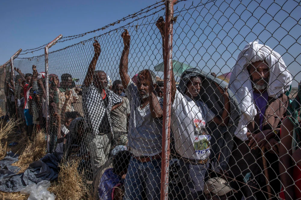 Tigray men, who fled the conflict in the Ethiopia's Tigray region, wait for UNHCR to distribute blankets at Hamdayet Transition Center in eastern Sudan on Nov. 21, 2020. (AP Photo/Nariman El-Mofty)