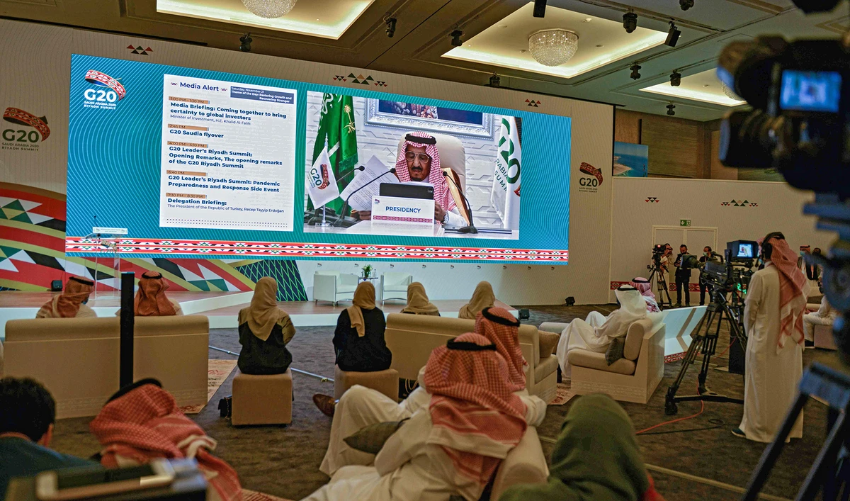Media persons gathered at the International Media Centre in Saudi Arabia's capital Riyadh on November 21, 2020 watch on a projected screen as King Salman gives an address opening the G20 summit, held virtually due to the COVID-19 coronavirus pandemic. (AFP)