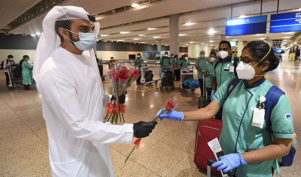 An Emirati official presents a rose to an Indian health worker, part of an 80 person medical team, upon their arrival at Dubai International Airport. (File/AFP)