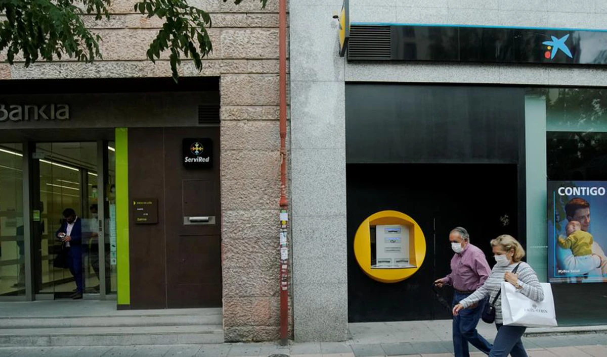 People walk past branches of Bankia and Caixabank in Madrid, Spain, September 18, 2020. (Reuters)