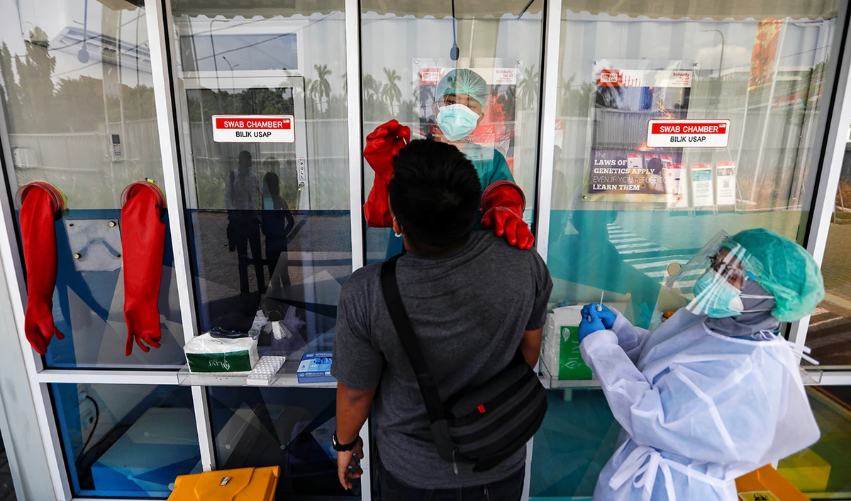 Medical workers wearing personal protective equipments (PPE) utilize a swab chamber as they collect a swab sample from a man to be tested for the coronavirus disease (COVID-19), as the outbreak continues in Jakarta, Indonesia, Indonesia, November 24, 2020. (Reuters)