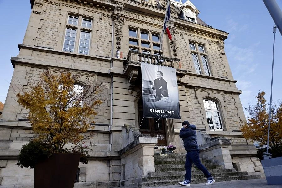 A pedestrian walks past a poster depicting French teacher Samuel Paty placed on the facade of the city hall in Conflans-Sainte-Honorine, 30kms northwest of Paris, on November 3, 2020. (File/AFP)