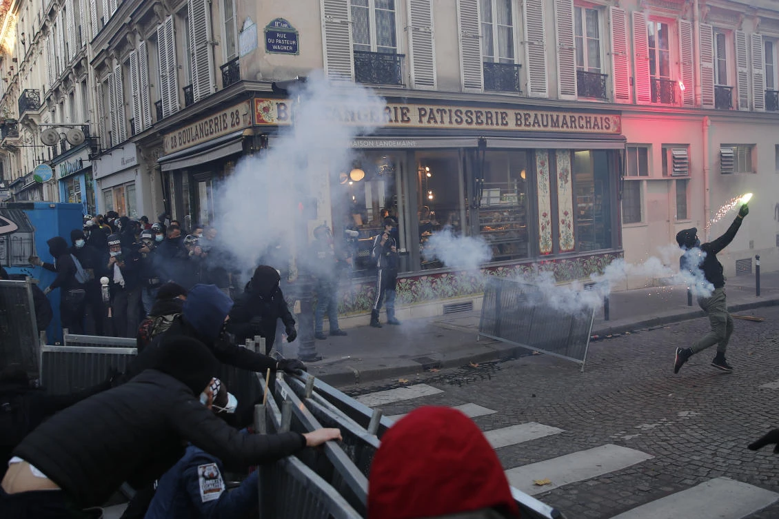 A demonstrator throws a flare during a demonstration against a security law that would restrict sharing images of police, Saturday, Nov. 28, 2020 in Paris. (AP)
