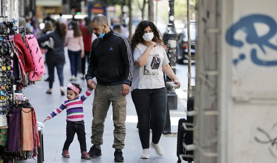 Mask-clad shoppers walk past shops in Beirut's Hamra street on May 7, 2020, as Lebanon gradually eases its lockdown measures against the spread of COVID-19 coronavirus. (AFP)