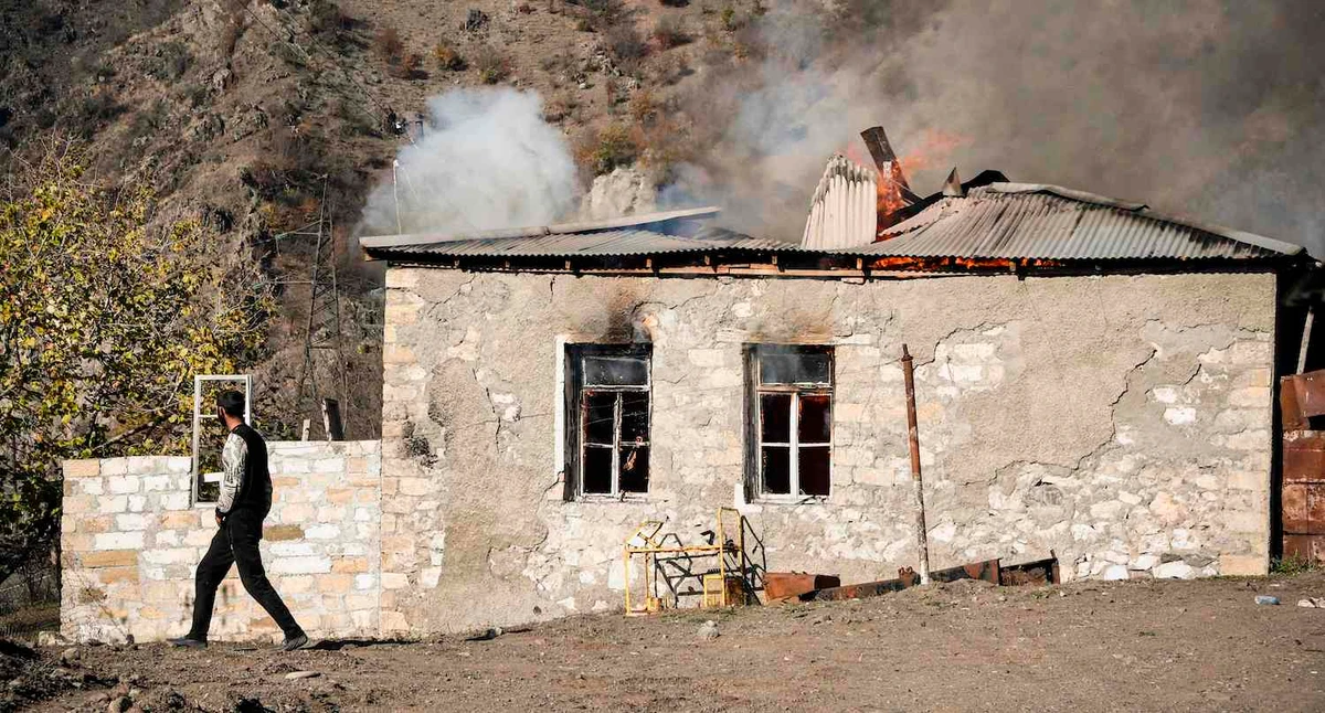 A man walks past a house burning in the village of Charektar outside the town of Kalbajar on November 14, 2020, during the military conflict between Armenia and Azerbaijan over Nagorno-Karabakh. (AFP)
