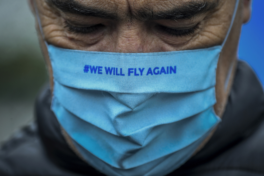 A TAP Air Portugal employee wearing a face mask reading "We will fly again" takes part in a protest against job cuts at TAP airline headquarters in Lisbon on December 9, 2020. (AFP)