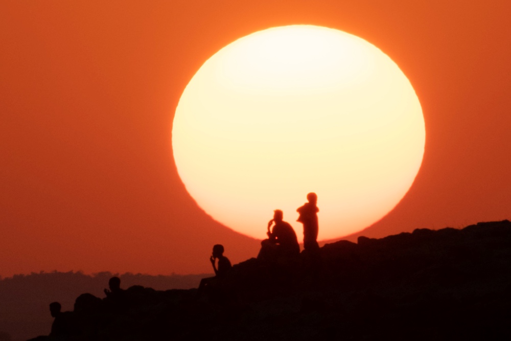 Ethiopian refugees who fled the Ethiopia's Tigray conflict watch the sunset on a hill at the Um Raquba refugee camp in Sudan's eastern Gedaref state on December 12, 2020. (AFP)