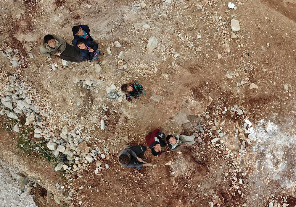 Syrian displaced children smile as their picture is taken by a drone at a camp near the city of Sarmin, in the rebel-held northwestern Syrian province of Idlib, on December 14, 2020. (AFP)