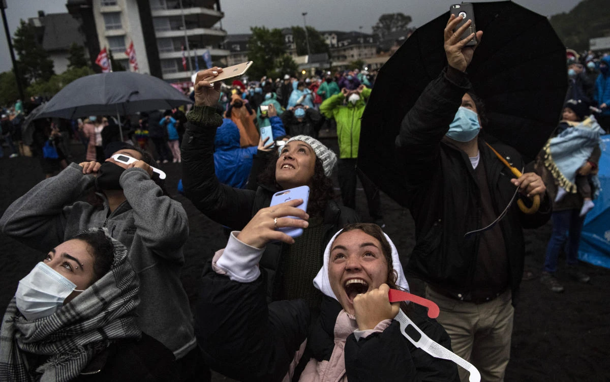 People watch the total solar eclipse on the banks of Villarrica lake in Pucon, southern Chile, on December 14, 2020. The hopes of thousands of tourists and residents in Chile's south saw their hopes of watching a total eclipse of the sun shrink as heavy rain fell on Monday just hours before the expected event.Martin BERNETTI / AFP