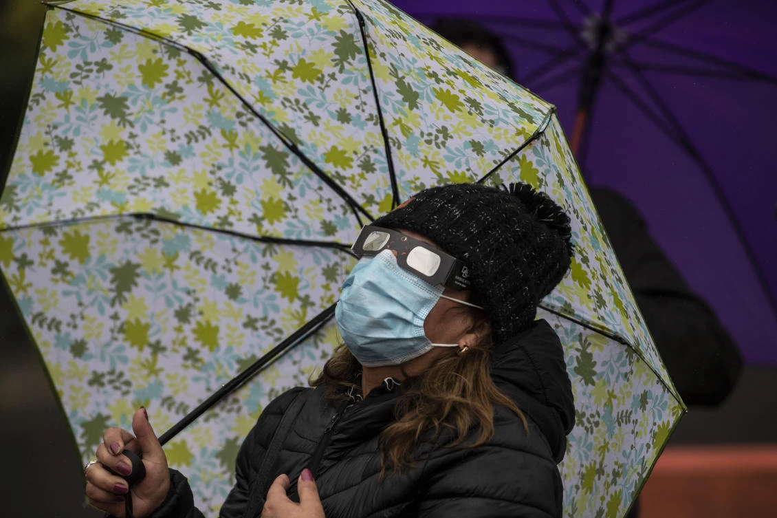 A woman watches the total solar eclipse on the banks of Villarrica lake in Pucon, southern Chile, on December 14, 2020. The hopes of thousands of tourists and residents in Chile's south saw their hopes of watching a total eclipse of the sun shrink as heavy rain fell on Monday just hours before the expected event.MARTIN BERNETTI / AFP