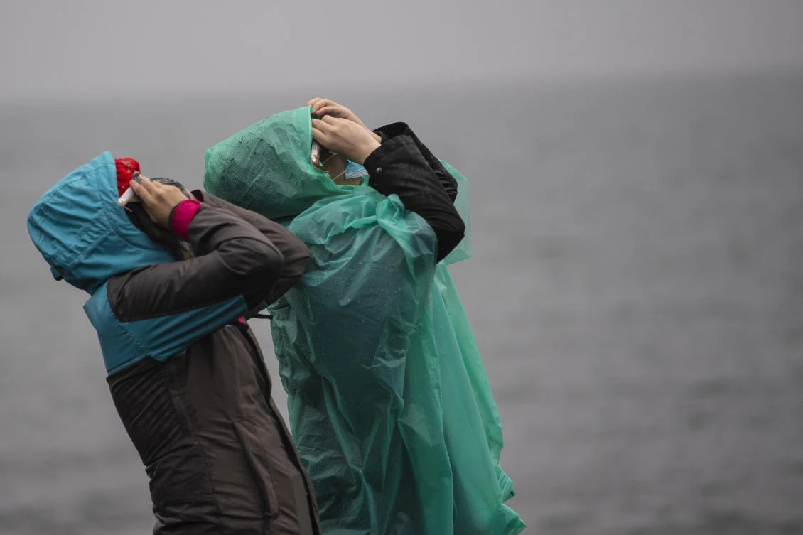 People watch the total solar eclipse on the banks of Villarrica lake in Pucon, southern Chile, on December 14, 2020. The hopes of thousands of tourists and residents in Chile's south saw their hopes of watching a total eclipse of the sun shrink as heavy rain fell on Monday just hours before the expected event.Martin BERNETTI / AFP