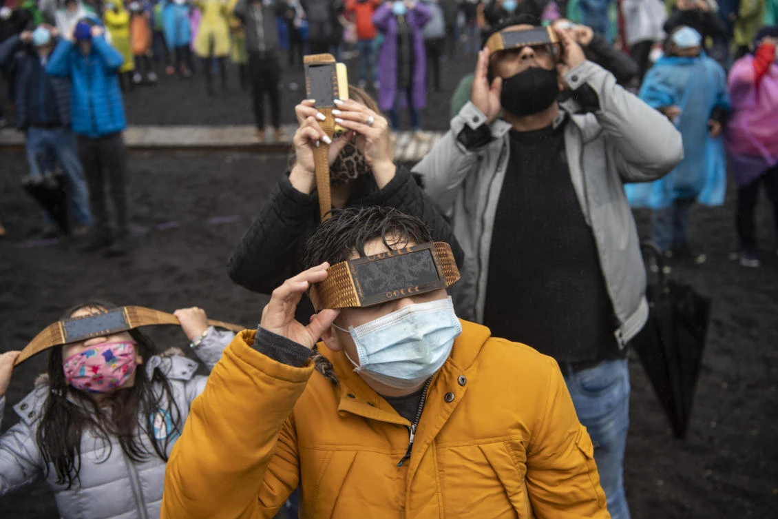 People watch the total solar eclipse on the banks of Villarrica lake in Pucon, southern Chile, on December 14, 2020. The hopes of thousands of tourists and residents in Chile's south saw their hopes of watching a total eclipse of the sun shrink as heavy rain fell on Monday just hours before the expected event.MARTIN BERNETTI / AFP