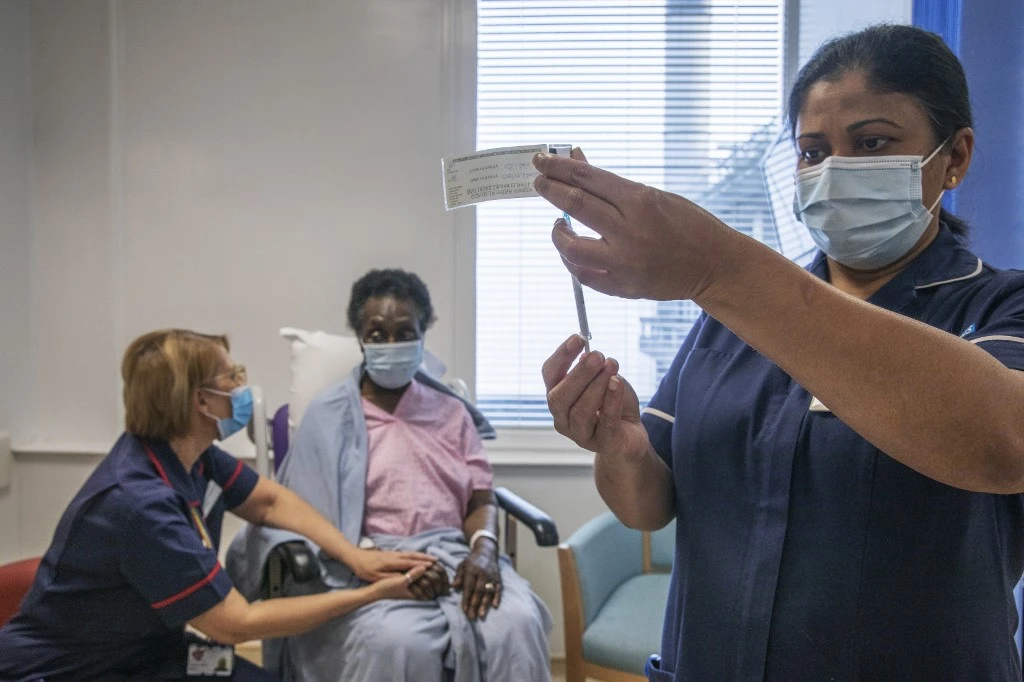 Senior nurse Dilhani Somaweera administers the Pfizer-BioNTech COVID-19 vaccine to Josephine Faleye, center, as Britain began its biggest vaccination program history. (AFP)