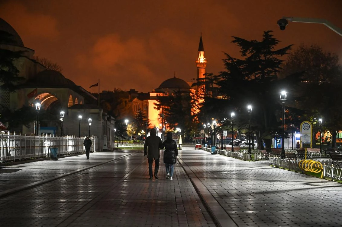 People walk on the deserted Sultanahmet square in Istanbul during a night-time curfew on December 1, 2020. (AFP)