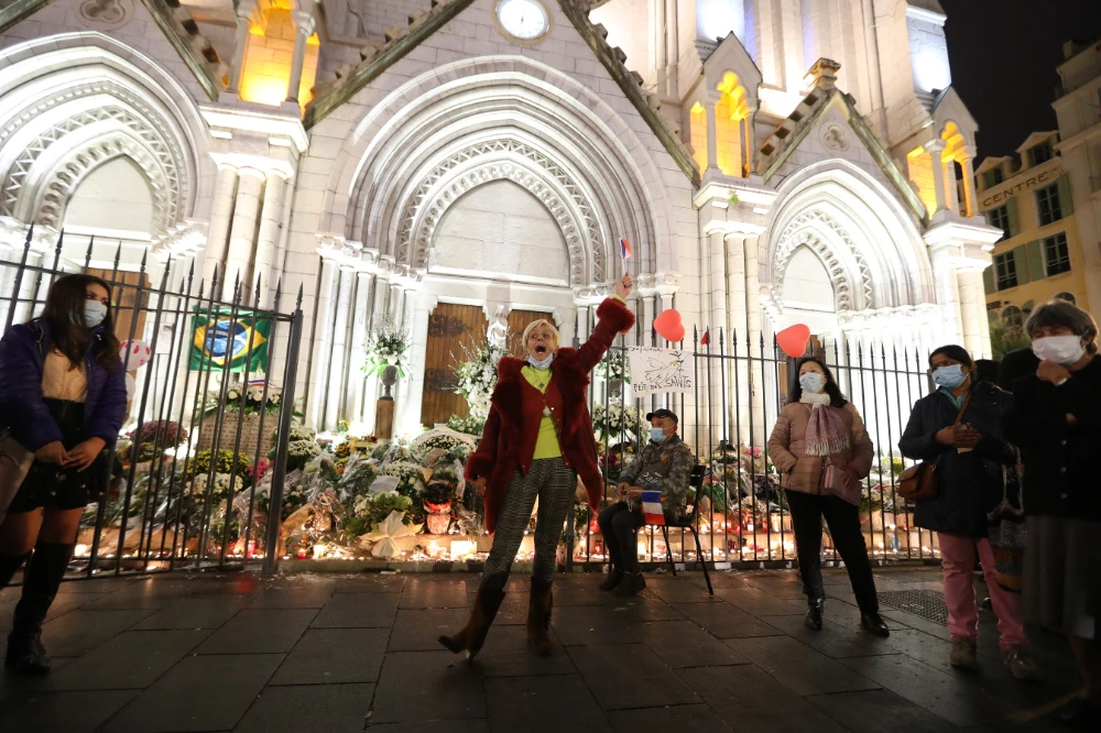 A woman sings the "Marseillaise", the French national anthem, outside Notre-Dame de l'Assomption Basilica in Nice on October 31, 2020, to pay tribute to the victims two days after a knife attacker killed three people, cutting the throat of two, inside the church of the French Riviera city. (AFP)