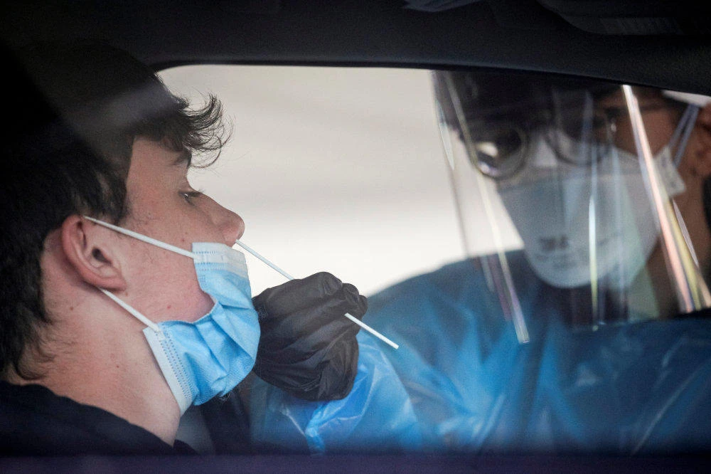 A health care worker gives a coronavirus test at a COVID drive-thru testing center at Bergen Community College, as the global outbreak of the coronavirus disease (COVID-19) continues, in Paramus, New Jersey, on December 3, 2020. (REUTERS/Brendan McDermid)