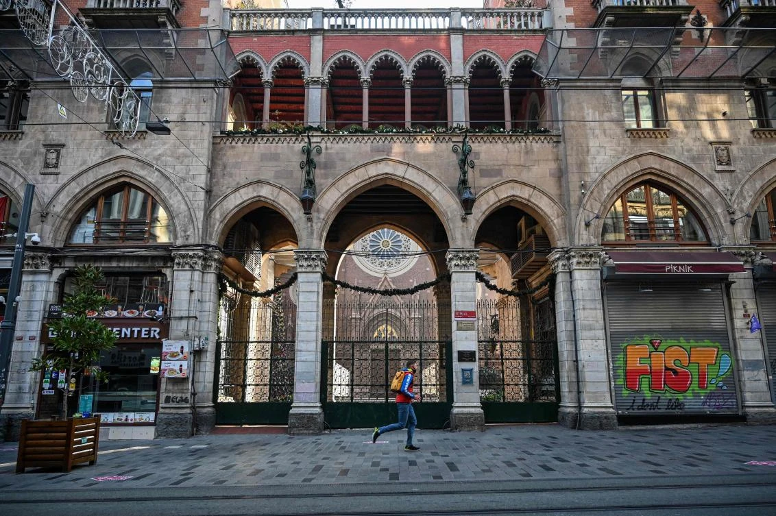 A man runs in a deserted Istiklal avenue in Istanbul during a week-end curfew aimed at curbing the spread of the Covid-19 pandemic caused by the novel coronavirus, December 5, 2020. (AFP)