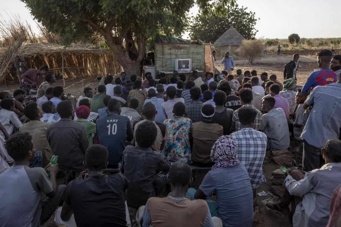 Tigranyan men who fled the conflict in Ethiopia's Tigray region, gather to watch the news on a television, at Umm Rakouba refugee camp in Qadarif, eastern Sudan, Saturday, Dec. 5, 2020. (AP)