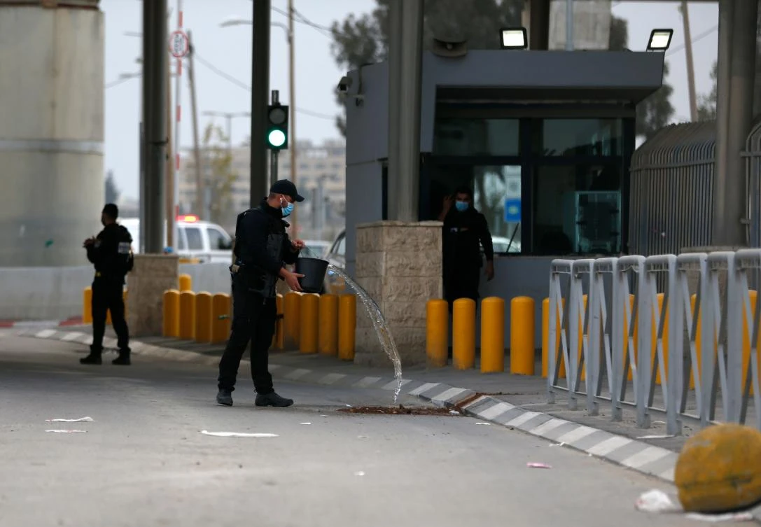 An Isaeli soldier cleans the blood stains at the spot where a Palestinian suspected of attacking troops was shot and wounded at the Qalandia checkpoint on the crossing between the West Bank city of Ramallah and Israeli-annexed east Jerusalemon on December 7, 2020. (AFP)