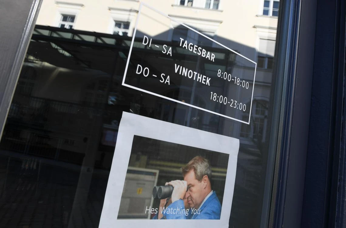 Above, a poster of Bavaria’s State Premier Markus Soeder with binoculars reading ‘Hes watching you’ in front of a entrance of a closed bar in the city of Rosenheim, southern Germany, on Dec. 7, 2020. (AFP)