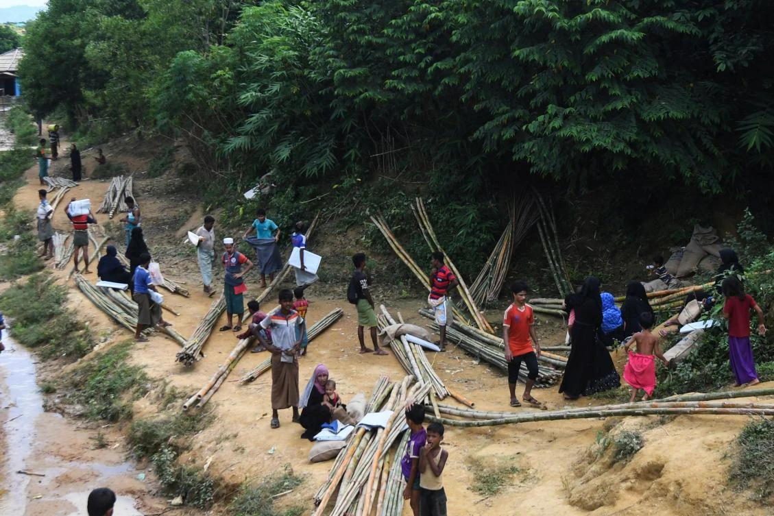 In this file photo taken on October 15, 2020, Rohingya refugees collect bamboo poles and other relief supplies at Kutupalong refugee camp in Ukhia, Bangladesh. (AFP)
