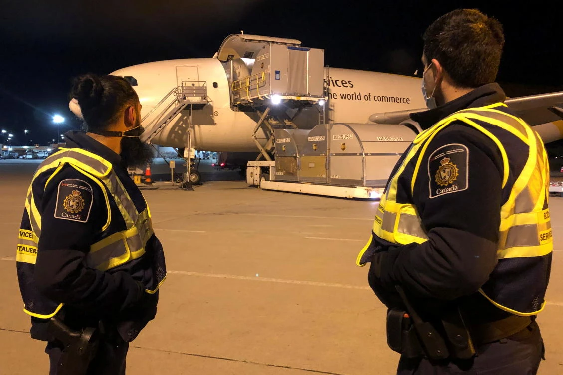 Canada Border Services Agency officers watch as the country’s first batch of Pfizer/BioNTEch coronavirus vaccines arrives at Montreal-Mirabel International Airport in Montreal on Dec. 13, 2020. (CBSA via Reuters)
