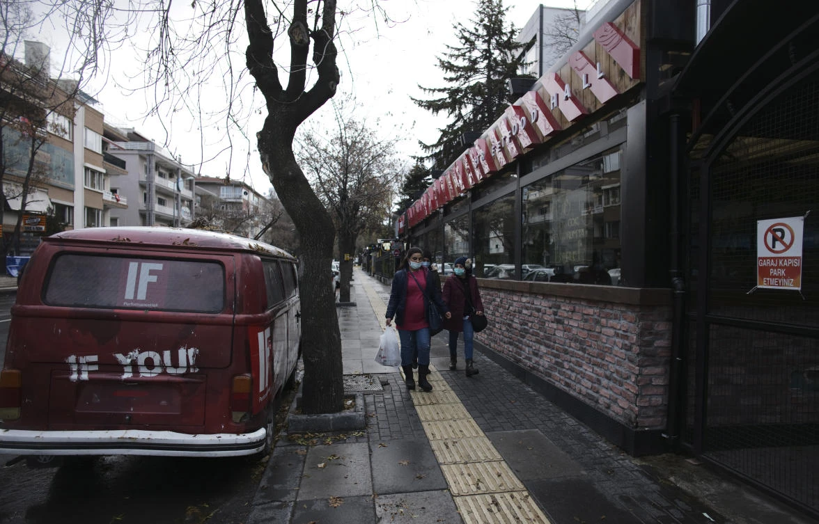 People wearing masks to help protect against the spread of coronavirus, walk during a two-day weekend curfew, in Ankara, Turkey, Sunday, Dec. 13, 2020. (AP Photo/Burhan Ozbilici)