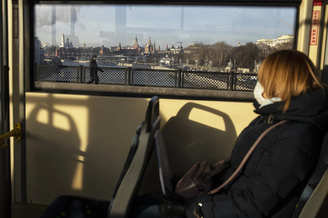 A woman wearing a face mask to protect against coronavirus rides on a tram with the Kremlin in the background in Moscow, Russia, Friday, Dec. 11, 2020. (AP)