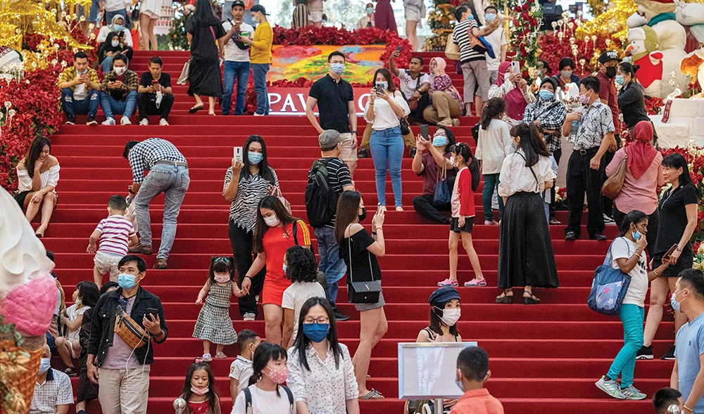 Shoppers wearing face masks, amid concerns over the spread of the COVID-19 coronavirus, spend time along the staircase of a shopping mall in Kuala Lumpur. (AFP)
