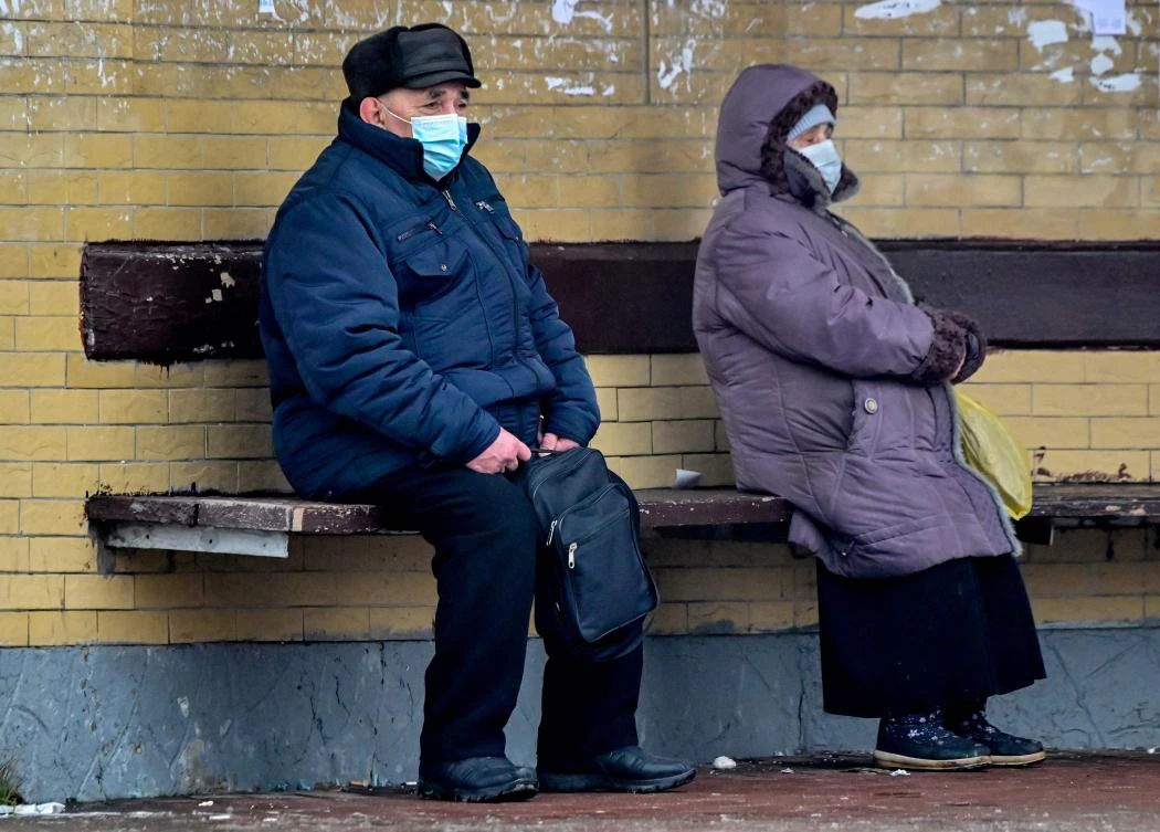 People wearing face masks to protect against the coronavirus disease wait for a bus at a bus stop in the town of Chekhov, some 70 km outside Moscow, on December 21, 2020. (AFP)
