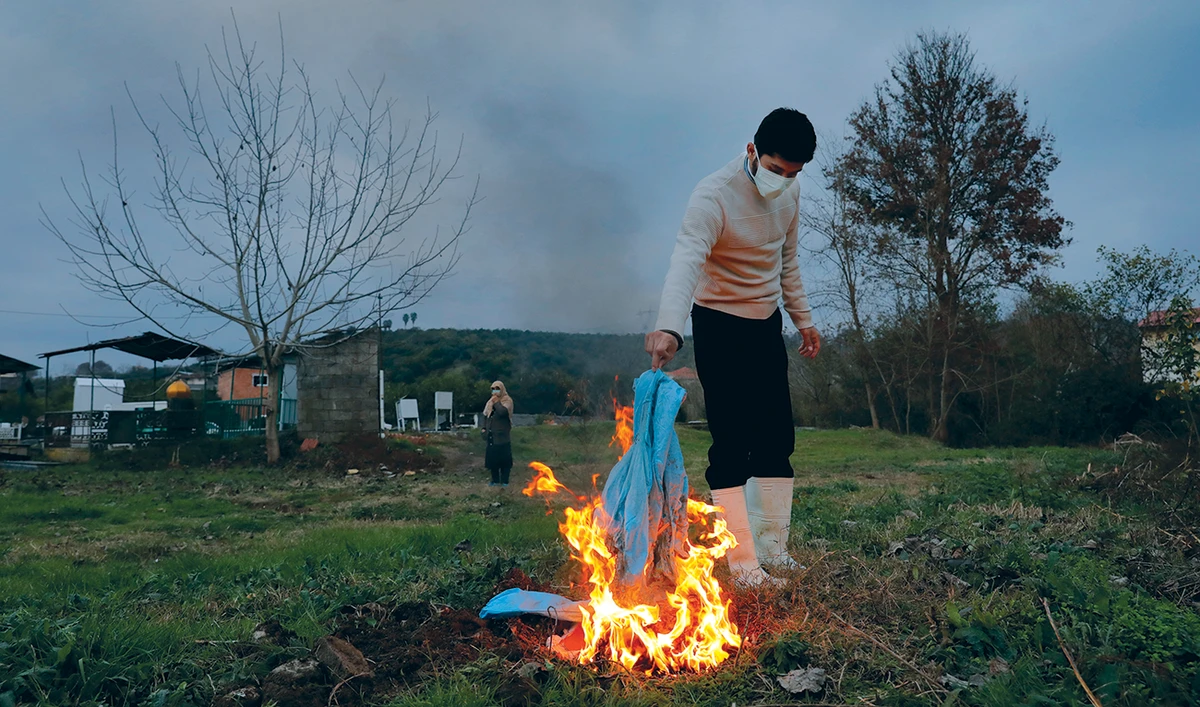 A volunteer cleric burns his protective clothes after the funeral of a COVID-19 patient at a cemetery in the Haji Kola village near the city of Ghaemshahr, Iran. (AP)