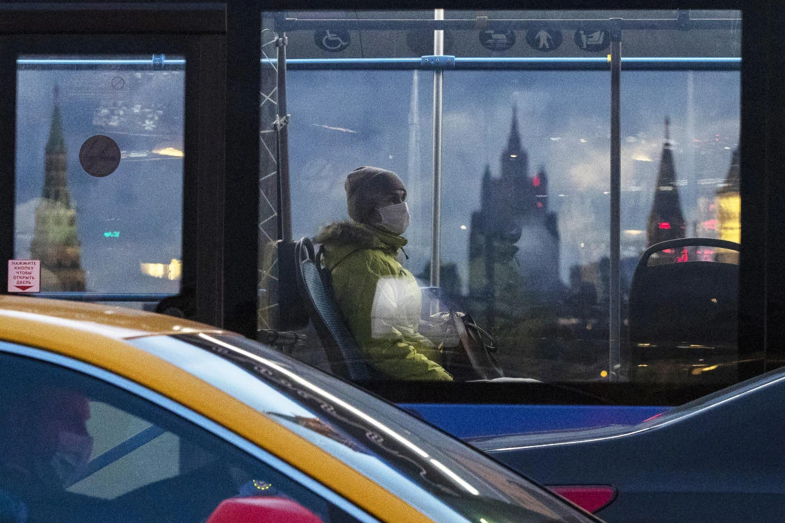 A woman wearing a face mask to protect against coronavirus, rides on a bus, with Kremlin’s towers, left and right, and Russian Foreign Ministry building, center, in the background, in Moscow, Russia, Wednesday, Dec. 23, 2020. (AP)