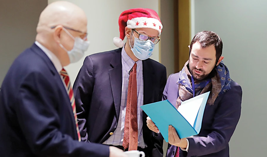 A colleague wears a Christmas hat as he speaks with EU ambassadors and representatives during a special meeting of Coreper, at the European Council building in Brussels on Friday. (AP)