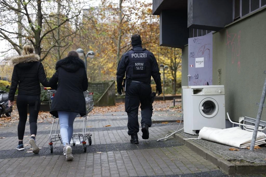 Policemen escort two neighbors pushing their shopping cart in a residential building in Berlin Kreuzberg’s district during raids of properties on Nov. 17, 2020. (File/AFP)