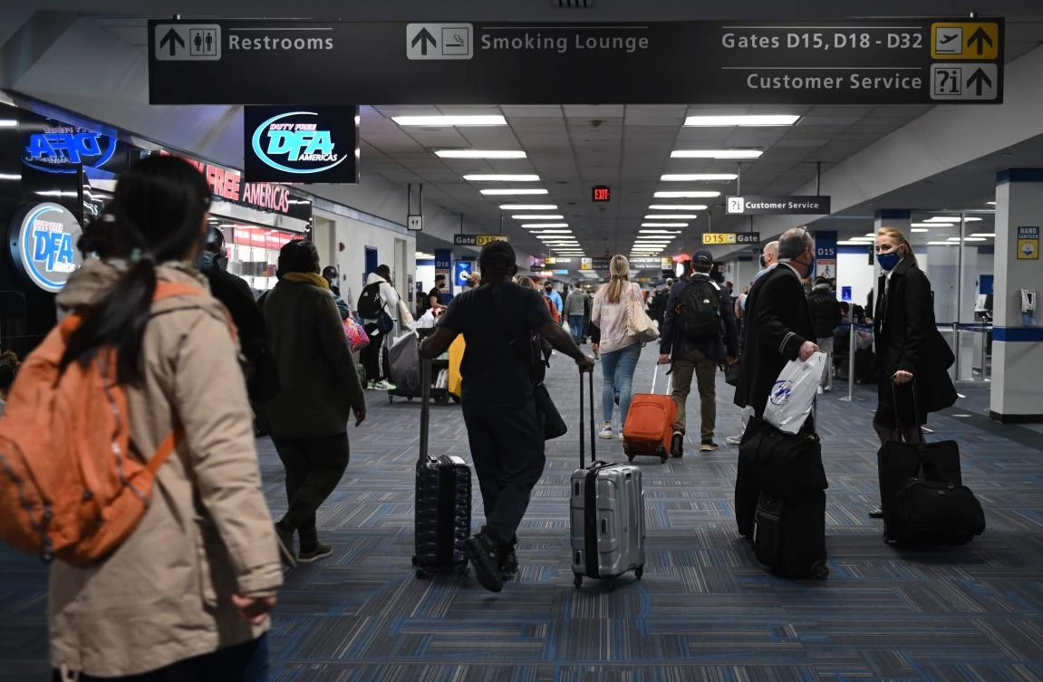 Passengers walk through a crowded terminal at Dulles International airport in Dulles, Virginia on December 27, 2020 amid the Coronavirus pandemic. Top US government scientist Anthony Fauci warned today the worst of the pandemic may be yet to come, driving the country to a "critical point" as holiday travel spreads the coronavirus. / AFP / ANDREW CABALLERO-REYNOLDS
