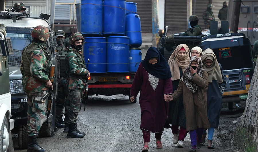 Indian army soldiers stand guard as pedestrians walk past on the outskirts of Srinagar on November 26, 2020. (AFP)