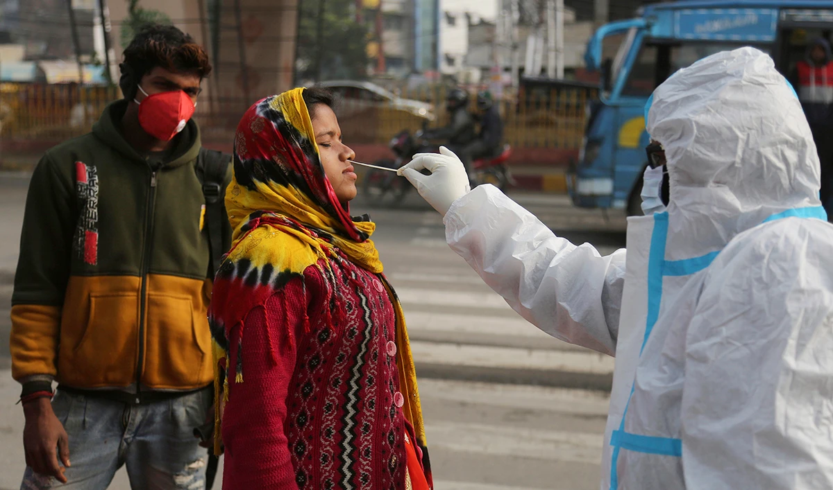 A health worker collects a swab sample from a woman to test for COVID-19. In preparation for a full roll-out India began a dry run for vaccination on Monday. (AP)