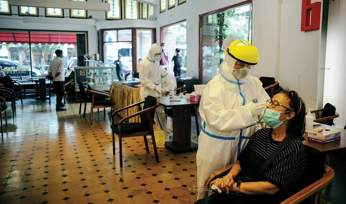 Healthcare workers take a rapid antigen sample from a visitor amid the coronavirus disease (COVID-19) pandemic in Bandung, West Java, Indonesia. (Reuters)