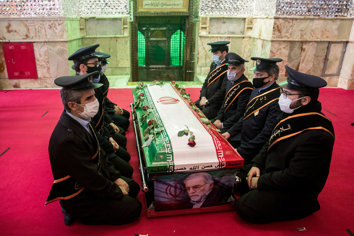 Mourners sit next to the coffin of Iranian nuclear scientist Mohsen Fakhrizadeh, during the burial ceremony at the shrine of Imamzadeh Saleh, in Tehran, Iran November 30, 2020. (Reuters)