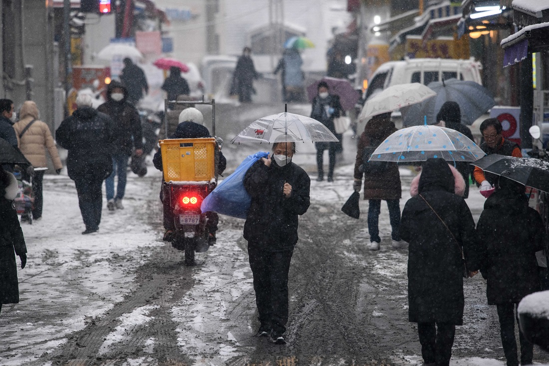 A man shelters beneath an umbrella during a snow fall in in Seoul on Jan. 12, 2021. (AFP)