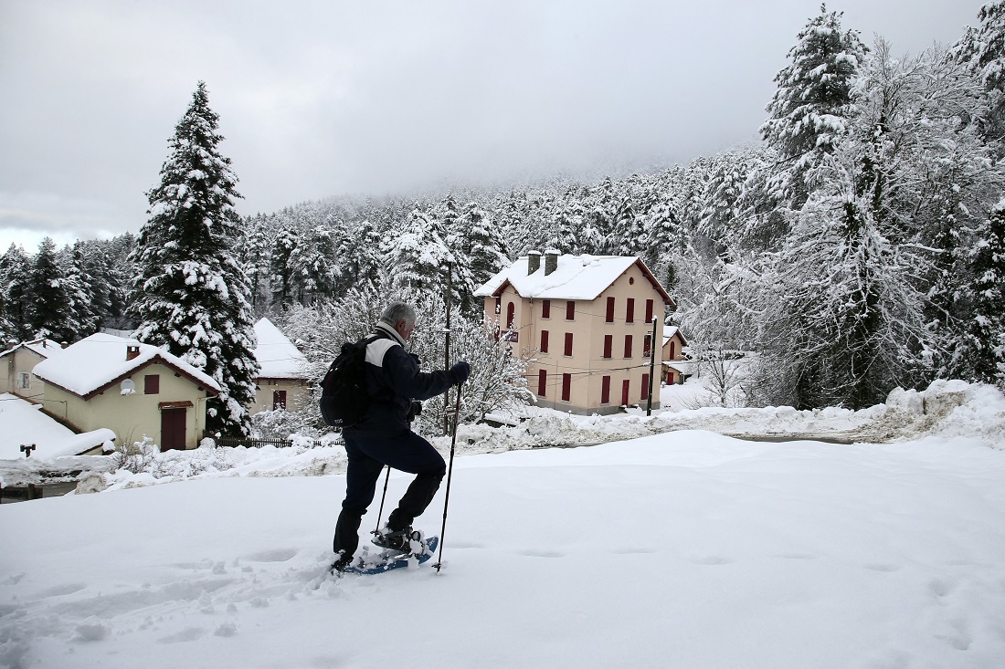 A man walks with snow shoes close from Vizzavona train station, on Jan. 11, 2021 on the French Mediterranean island of Corsica, following heavy snow falls over southern Europe. (AFP)