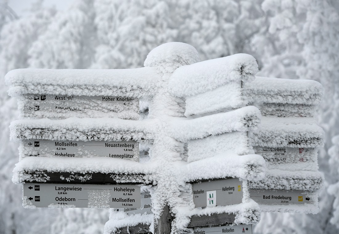 A signpost for trails is covered in snow at the Kahler Asten mountain in Winterberg, western Germany, on Jan. 10, 2021, amid the ongoing novel coronavirus / COVID-19 pandemic. (AFP)